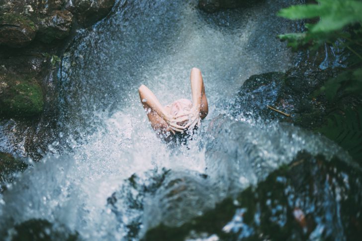 meisje wast zich onder waterval