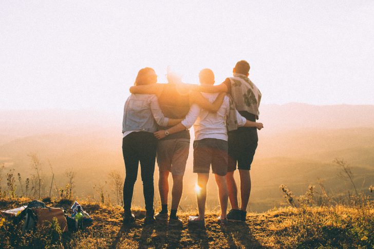 groep vrienden omhelzen elkaar bij zonsondergang