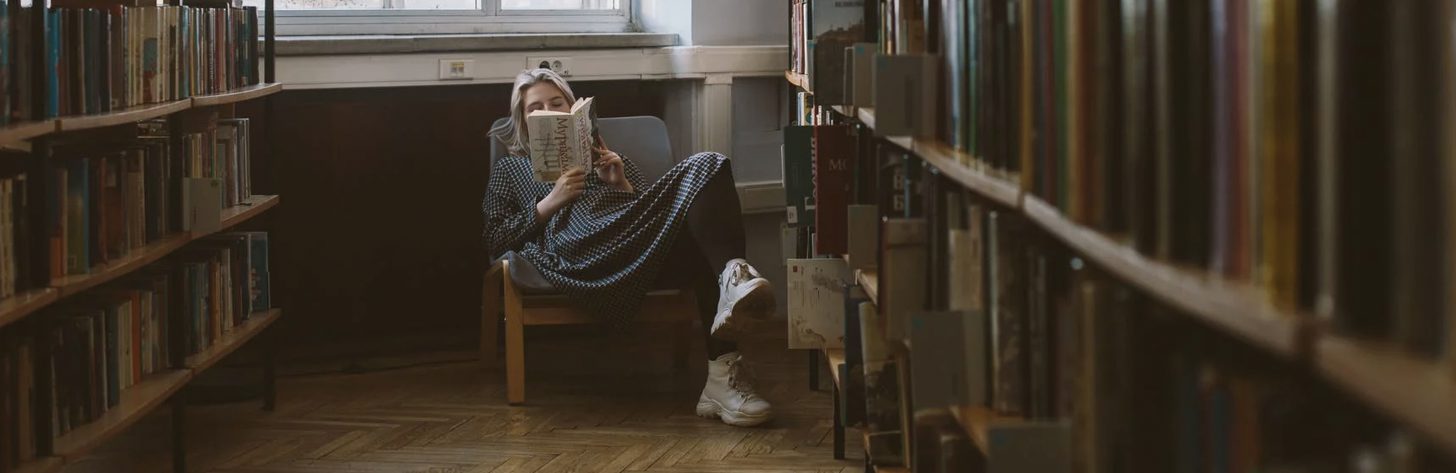 meisje zit in een stoel en leest een boek