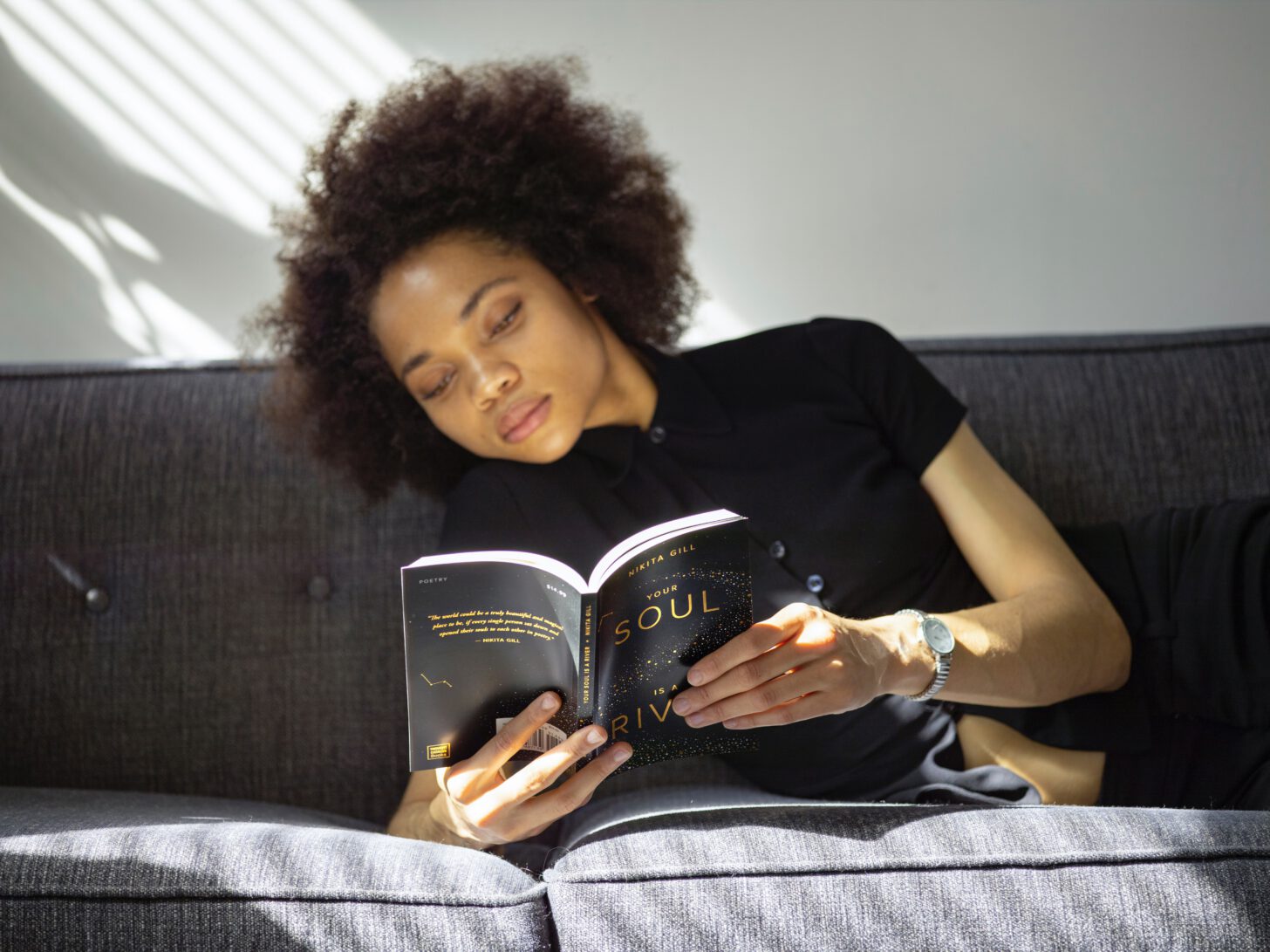 vrouw leest boek op bank