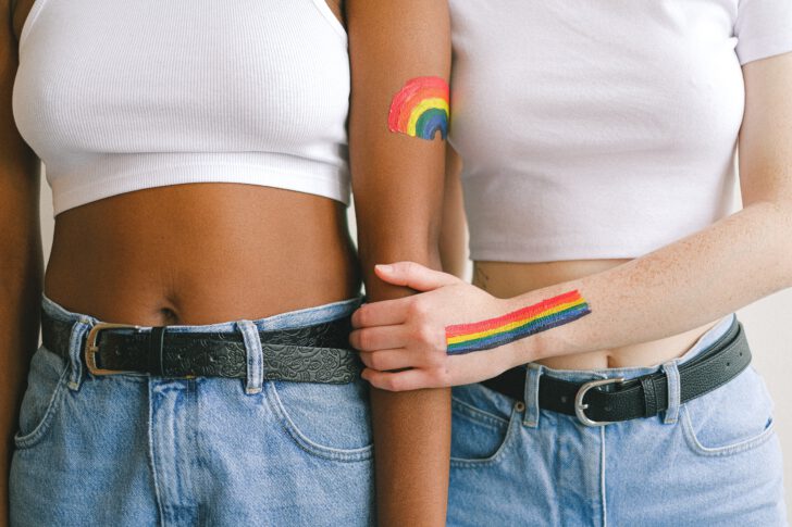 Vrouwen houden elkaar vast met regenboog op de arm