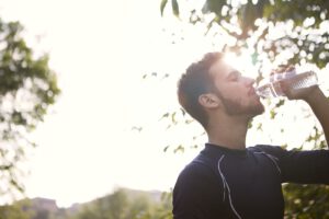 Hardlopende man die uit plastic flesje drinkt