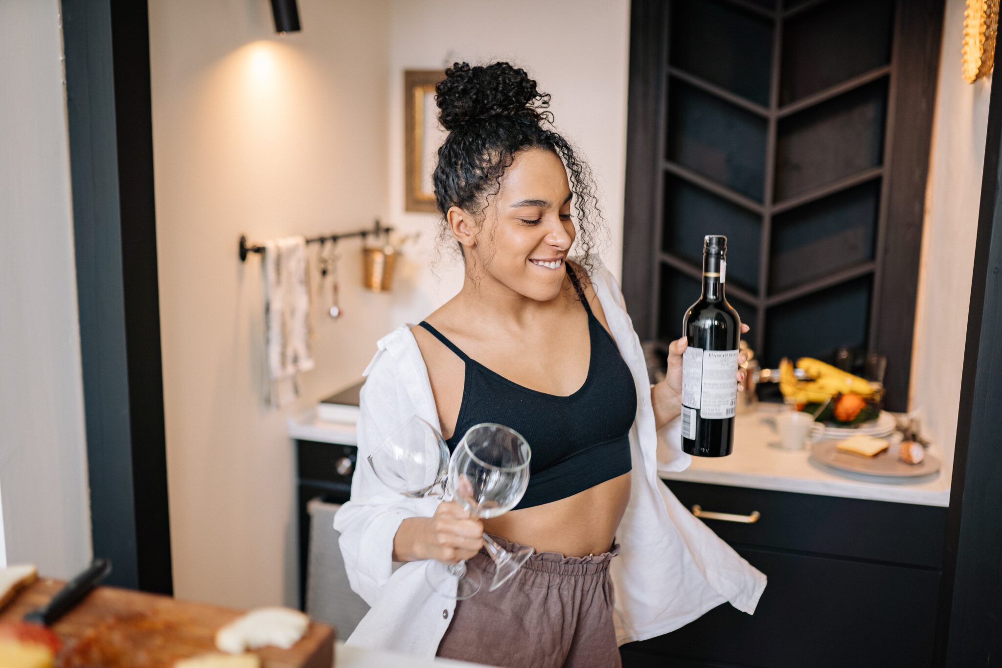 Vrouw die in de keuken danst met fles wijn