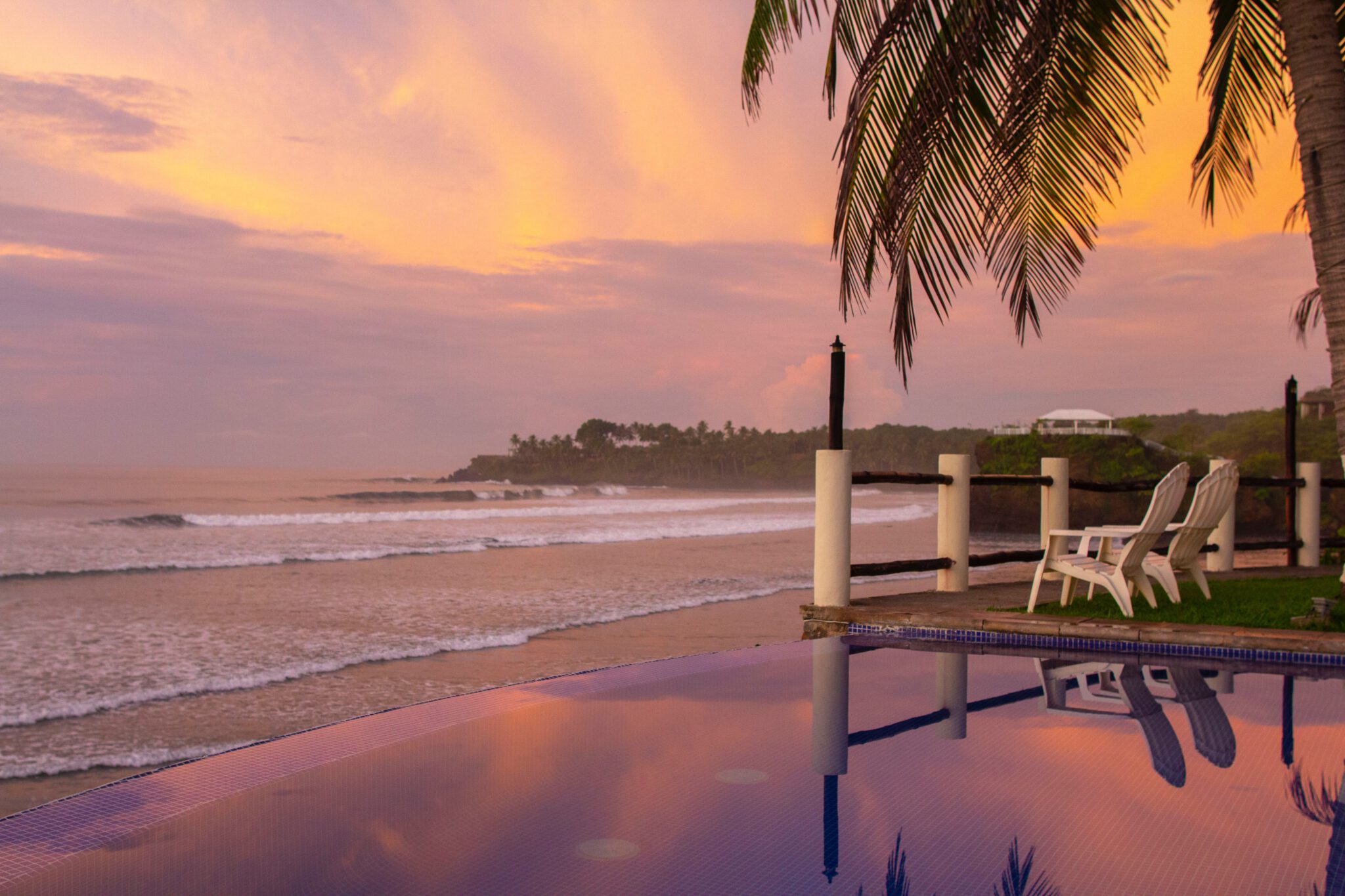 strand met palmbomen en een infinity pool